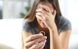 Warum. Frau hält Ehering in der Hand