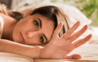 Pornoausstieg erleichtern. Frau betrachtet im Bett liegend ihren Ehering