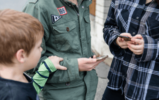 Sicherung. Zwei Teens am Smartphone und ein Kind schaut mit